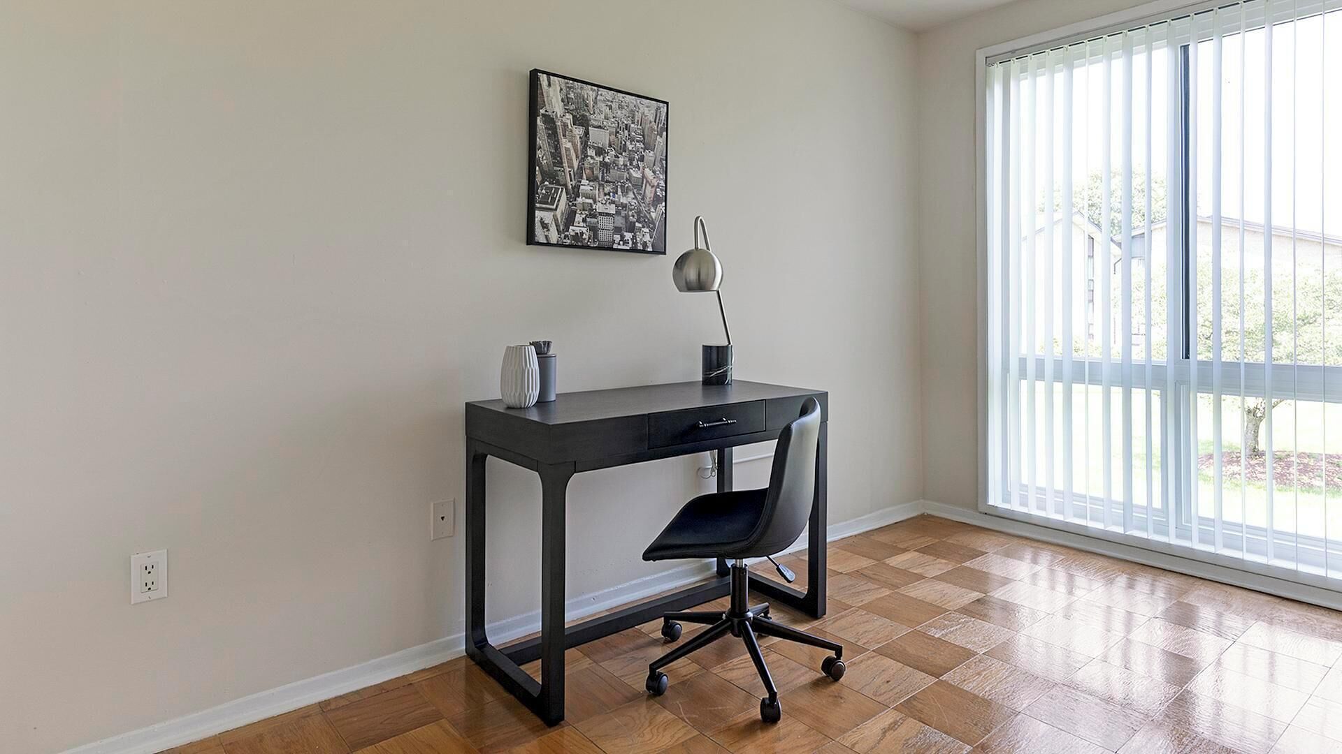 A room with a desk, chair, and a large window.