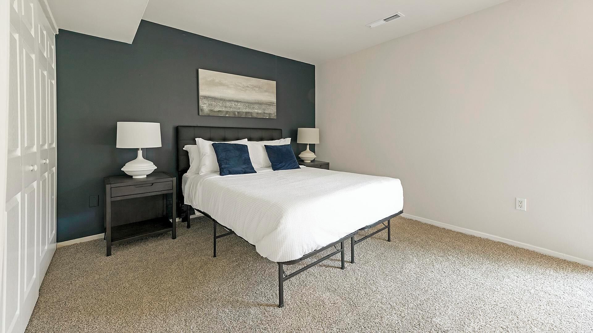 A bedroom with a bed, two bedside tables, and a nightstand.