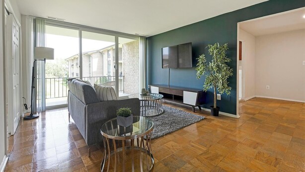 A modern living room with a sofa, glass coffee table, and a TV mounted on the wall.