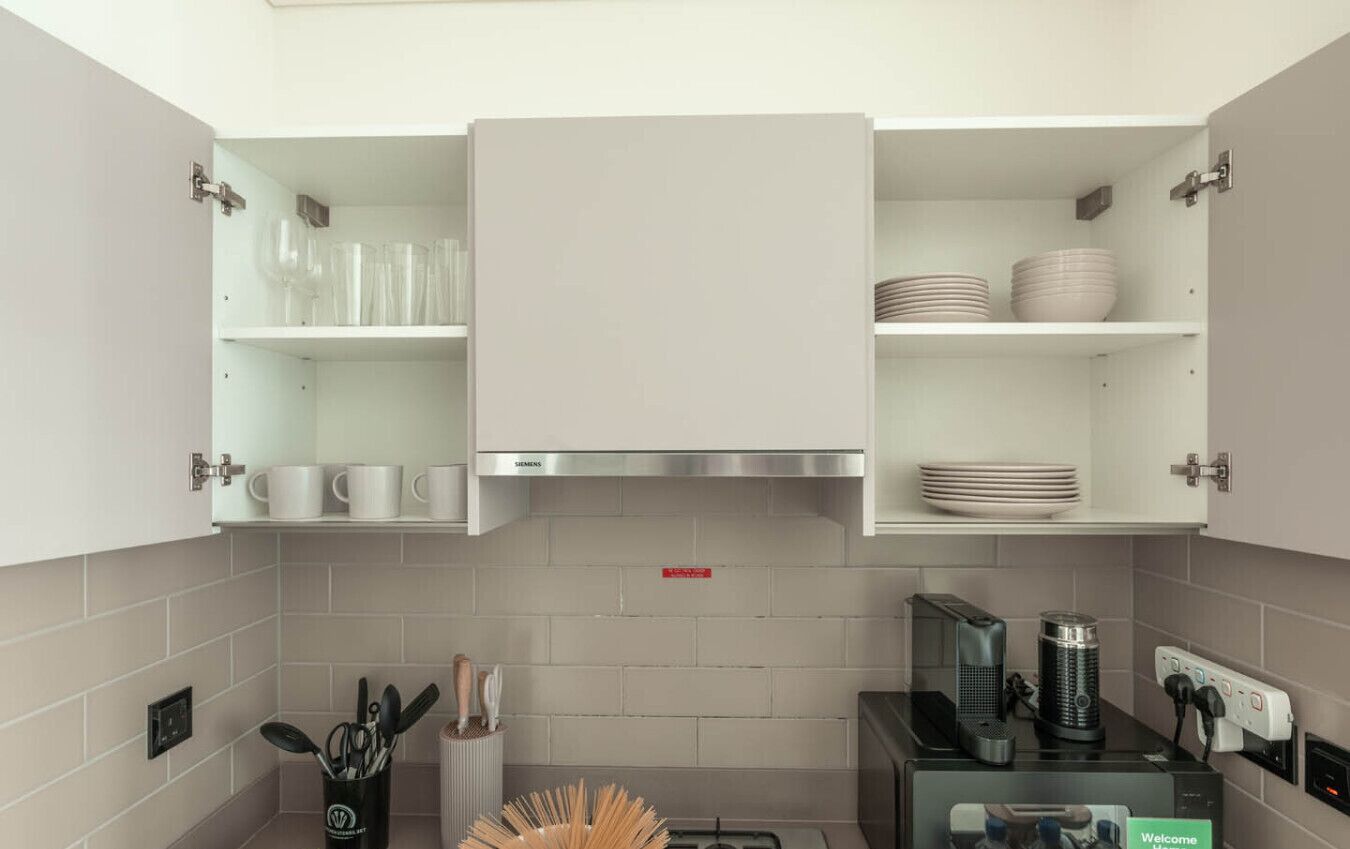 Une cuisine moderne avec des armoires blanches, une hotte de cuisinière en acier inoxydable et une machine à café.