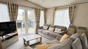 A cozy living room with a sofa set, a coffee table, and a flat-screen TV. - Relax with the whole family at this peaceful place to stay (Hoburne Holiday Park)