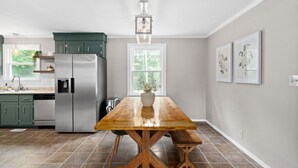 A modern kitchen with a central island, stainless steel appliances, and a farmhouse-style dining table.