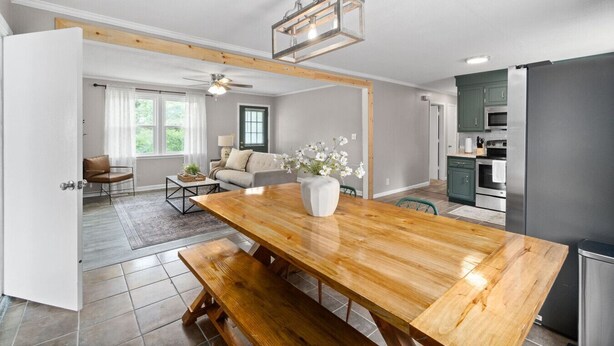A modern kitchen with stainless steel appliances, a wooden dining table, and a ceiling fan.