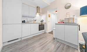 Ett modernt kök med vita skåp, en inbyggd ugn och en mikrovågsugn placerad på bänkskivan.