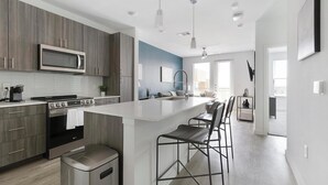 Una cocina moderna con una isla central, electrodomésticos de acero inoxidable y una zona de asientos con taburetes de bar.