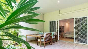 A room with a sliding glass door leading to a balcony, a wooden table with chairs, and a sofa.
