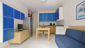 Un espacio habitable compacto con kitchenette, comedor y sofá.