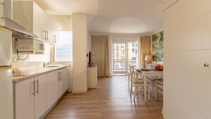 Eine moderne Küche mit weißen Schränken, einer Mikrowelle und einem Essbereich mit Tisch und Stühlen.