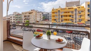Ein Balkon mit Tisch für zwei Personen, einem Blumentopf und Blick auf die Stadt.