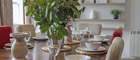 Enjoy a meal in style with a beautifully set table, complete with fine china and a lush green centerpiece.