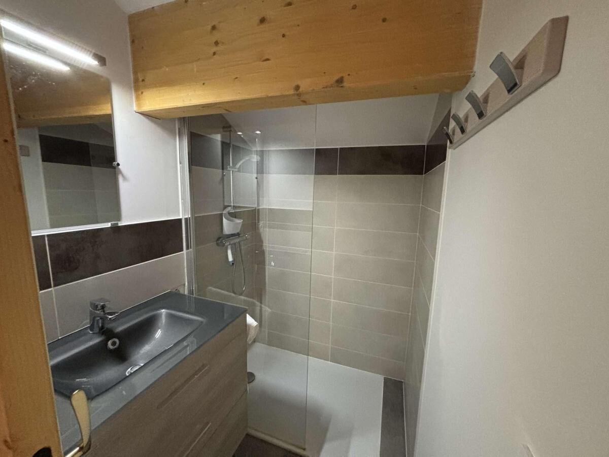 A bathroom with a sink, mirror, and shower.