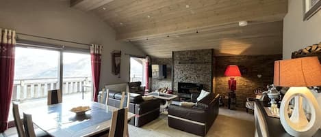 A spacious living area with a dining table, sofas, and a fireplace.
