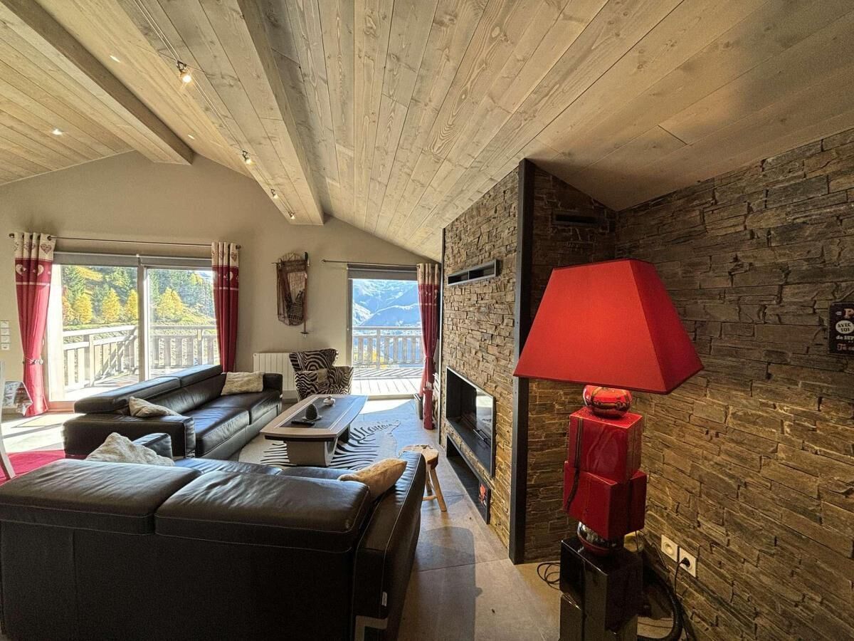 Un salon moderne avec une cheminée en pierre, un canapé en cuir et une grande fenêtre agrémentée de rideaux.