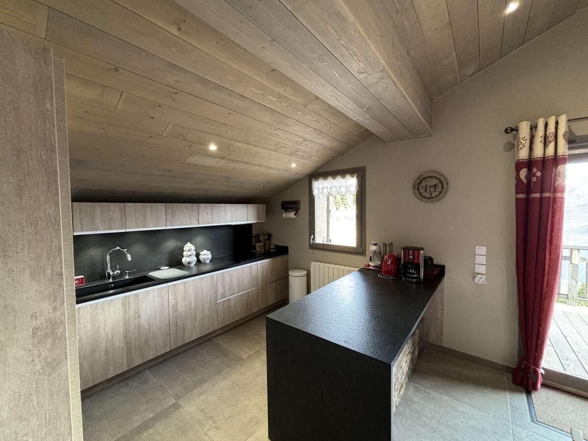 Una cocina moderna con armarios de madera, encimera negra y una ventana con cortinas.