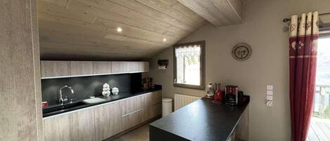 Una cocina moderna con armarios de madera, encimera negra y una ventana con cortinas.