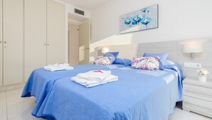 A hotel room with a large bed, a wardrobe, a painting, and a nightstand with a lamp.