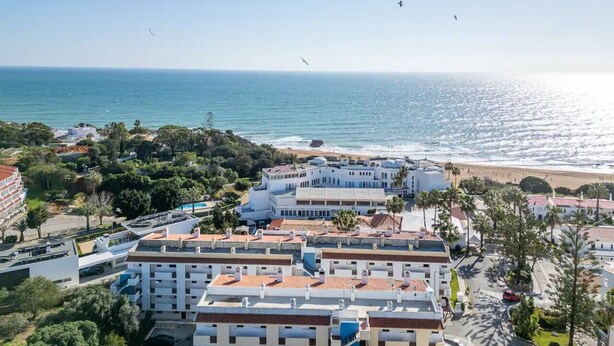 Ein Küstenhotel mit mehreren Gebäuden, einem Strand und blauem Himmel.