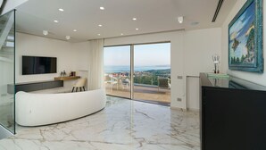 Una sala de estar moderna con un sofá curvo, un televisor de pantalla plana y un ventanal con vistas a la ciudad.