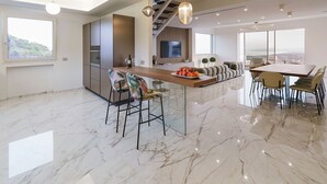 Una cocina moderna con una isla central, un comedor con una mesa grande y una zona de estar con un sofá y sillas.