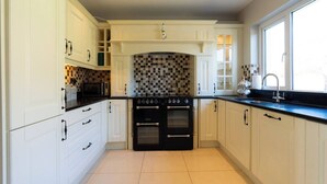 A modern kitchen with white cabinetry, a black stove, and a tiled backsplash.
