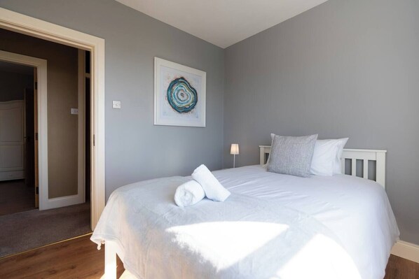Une chambre à coucher avec un lit, une porte et une œuvre d’art accrochée au mur.
