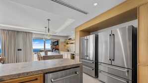 A modern kitchen with stainless steel appliances, a marble countertop, and wooden cabinetry.