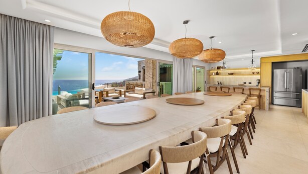 A modern kitchen with a large island, stainless steel appliances, and a view of the ocean.