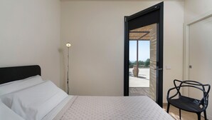 A bedroom with a bed, a chair, a floor lamp, and a door leading to an outdoor area. - Villa Miriam with swimming pool - My Rental Homes (Scicli)