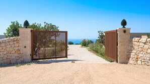 A gated entrance with a gravel path leading to a scenic view. - Villa Miriam with swimming pool - My Rental Homes (Scicli)