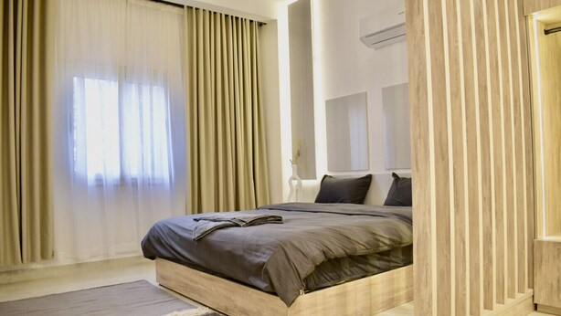 Une chambre à coucher moderne avec un lit, des rideaux et un plancher en bois.
