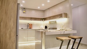 Une cuisine moderne dotée d’un plan de travail en marbre, d’un four encastré et d’un tabouret en bois.