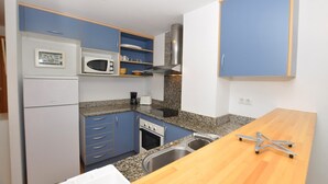 Una cocina compacta con gabinetes azules, un microondas, una estufa y un lavabo.