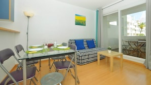 Una sala moderna con una mesa de comedor de vidrio, un sofá estampado en blanco y negro, y una pequeña mesa de madera.