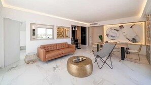 Un salon moderne comprenant un canapé, une table basse ronde et un coin repas avec des chaises et une table.