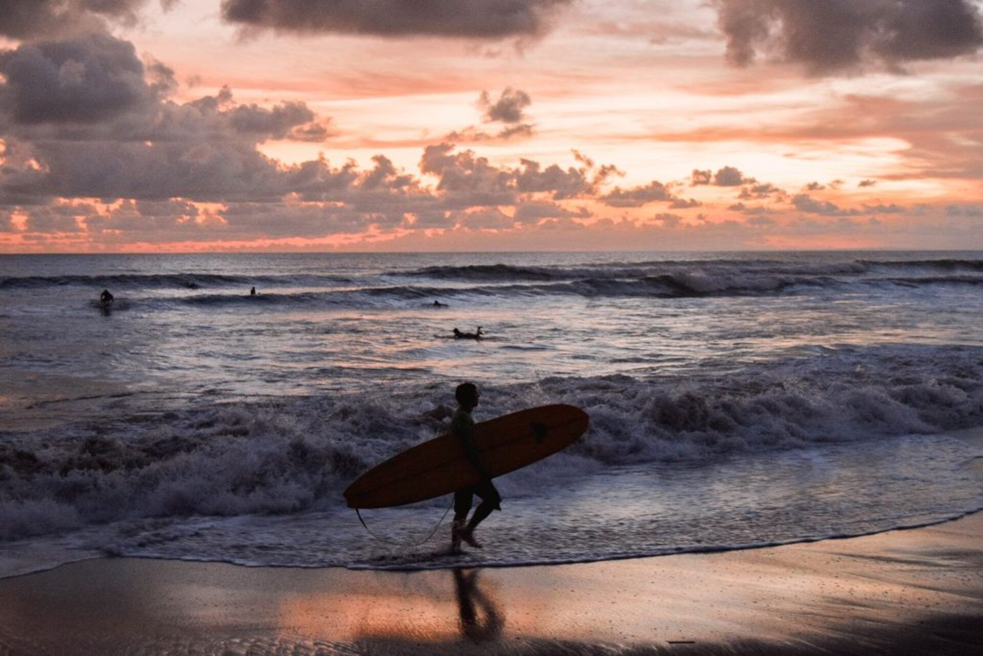 Une scène de plage avec des vagues et un coucher de soleil.
