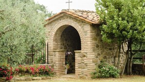 A stone chapel with an arched entrance, a cross on the roof, and a garden with flowers and trees. - Casa Raffaello - Four Bedroom Villa, Sleeps 8 (Citta di Castello)