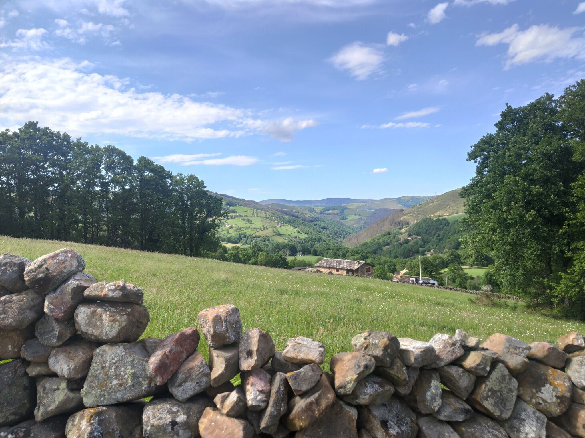 Eine Steinsäule, ein grasbewachsenes Feld und sanfte Hügel in der Ferne.
