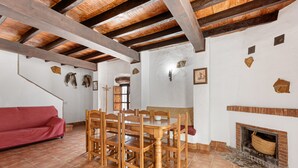 A dining area with wooden furniture, a fireplace, and a red sofa.