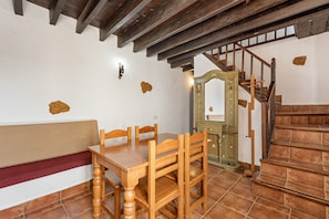Un comedor con una mesa y sillas de madera, un banco, una escalera y un espejo con marco decorativo.