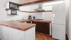 A kitchen with a built-in microwave, stove, and refrigerator, featuring a wooden ceiling and tiled backsplash. - Country House 'La Casa Grande' with Lake View, Shared Pool and Wi-Fi (Málaga)