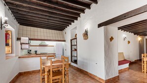 A kitchen with wooden chairs, a tiled floor, and a white wall with a shelf. - Country House 'La Casa Grande' with Lake View, Shared Pool and Wi-Fi (Málaga)