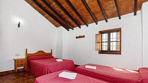 A room with two beds, a wooden ceiling, a window, and a nightstand. - Country House 'La Casa Grande' with Lake View, Shared Pool and Wi-Fi (Málaga)