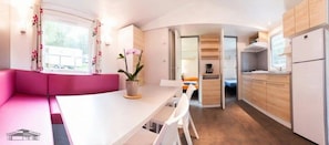 Una cocina compacta con armarios de madera, una encimera blanca y una zona de estar en tonos rosa.