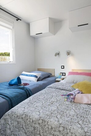 A bedroom with two beds, a window, and built-in cabinets. - ZEcamping 4* animé piscine couverte 500m plage sauna locatif TV BBQ (La Forêt-Fouesnant)