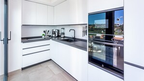 Eine moderne Küche mit weißen Schränken, einer schwarzen Arbeitsplatte und einem eingebauten Backofen.