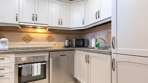 A modern kitchen with white cabinets, stainless steel appliances, and a patterned backsplash. - Stunning Views-Miraflores Apartment; Pass the Keys (Mijas)