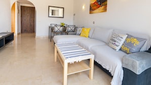 A modern living room with a sofa, a coffee table, and a dining area with chairs and a table. - Stunning Views-Miraflores Apartment; Pass the Keys (Mijas)