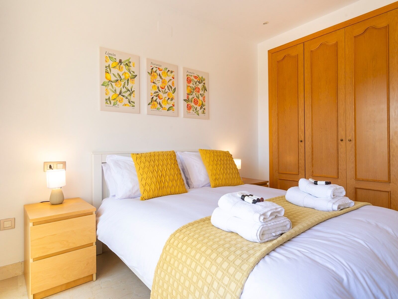 A neatly arranged bedroom with a bed, bedside tables, and a wardrobe.