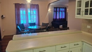 Un espace de vie compact comprenant une kitchenette, un coin repas et une petite chambre.