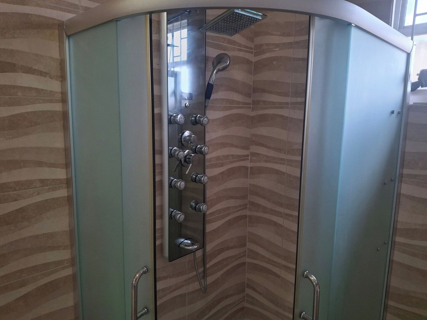Eine Dusche mit mehreren Bedienelementen und einer Glastür.